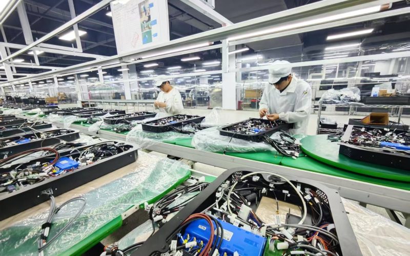 Workers on an assembly line alongside automated systems, illustrating the integration of human labor with smart manufacturing technologies